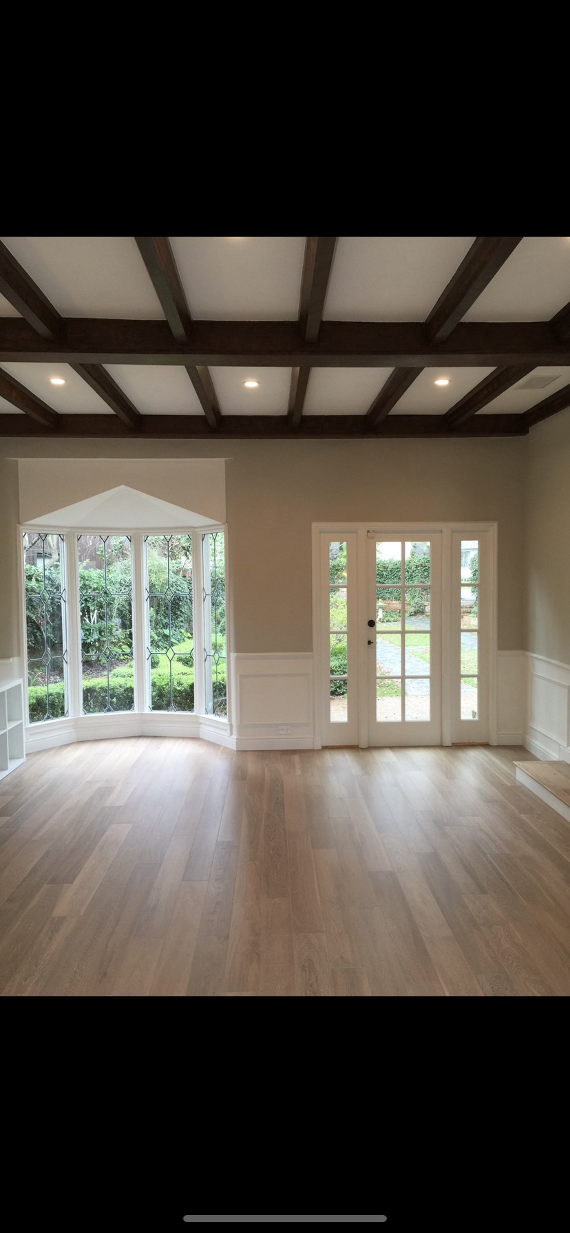Elegant living room with coffered ceiling and wide-plank light oak floor and staircase