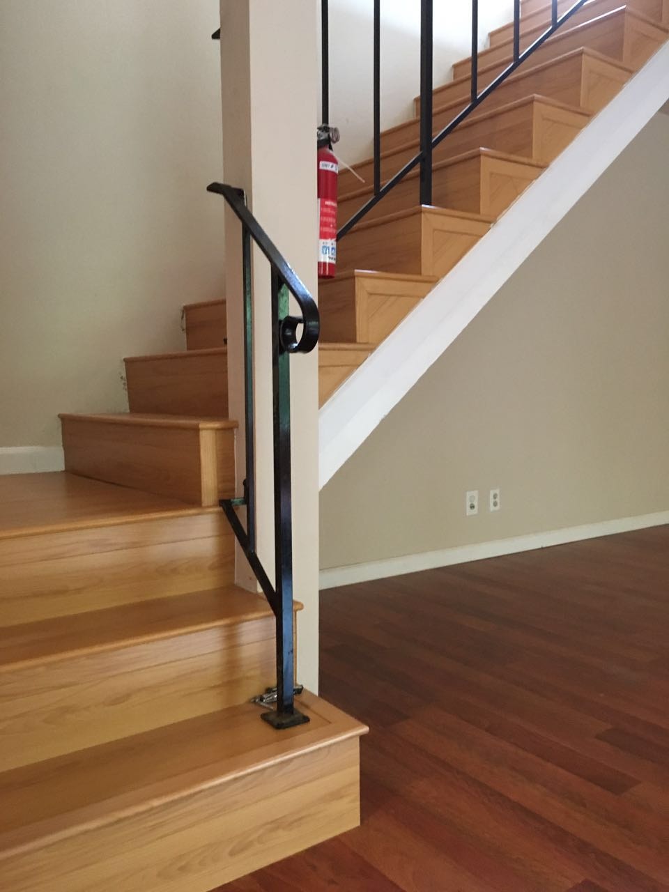 Oak staircase with iron railing and contrasting dark hardwood floor